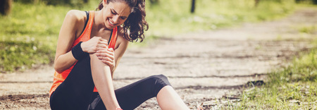 nainen karsii akillisesta polvikivusta lenkkeillessa